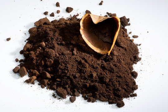 getrockneter Kaffeesatz  angeh&auml;uft,  mit  gebrauchtem Papierfilter auf hellem Untergrund