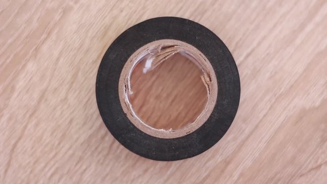 Putting boobin of insulating tape on table and taking it back