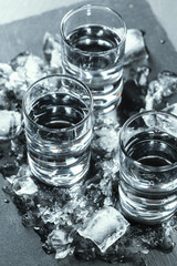 Cold vodka in shot glasses on a black background.