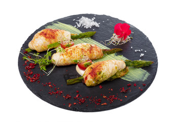 Asparagus rolled in grilled bacon served with sauce on dark plate