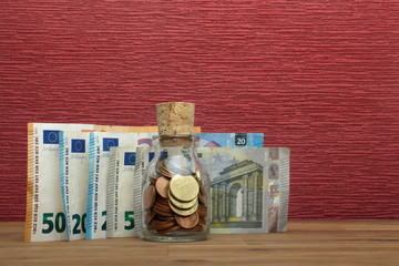 Euro coins and bill on the burgundy red background in a money box