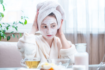 Obraz na płótnie Canvas Beautiful happy woman with cosmetic natural mask on her face looking at her skin. Skin care and Spa treatments at home