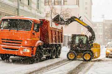 excavator load snow in truck. clearing streets of snow b