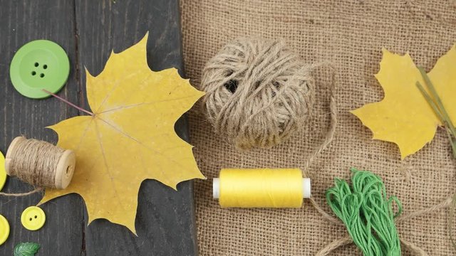 Decorative composition of accessories for sewing and needlework in the style of eco fashion on a wooden plank and burlap