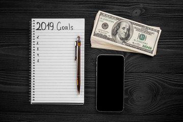 2019 GOALS on his notebook. New year resolutions concept. Top view.