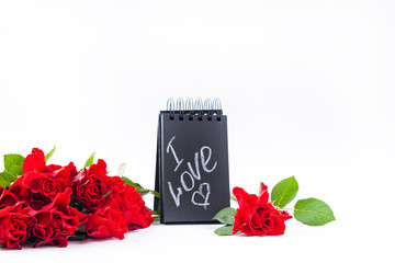 A bouquet of red roses and a letter with the text of love. Gift and flowers on a white background. The concept of lovers day and mother's day. Copy space.