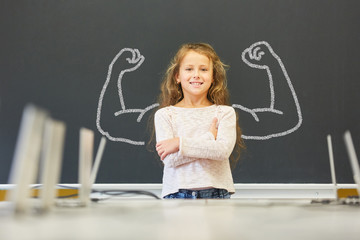 Mädchen in Schule steht vor Tafel mit Muskeln - obrazy, fototapety, plakaty