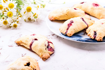 Homemade berries shortcakes, honeysuckle pastry pies on white cracked concrete background