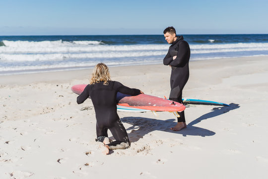 surf instructor with a student on the ocean. Surfer in a wet suit with a training board. Nazare, Portugal.