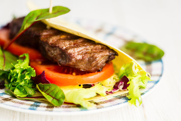 Mexican tortilla stuffed with beef steak and salad and vegetables