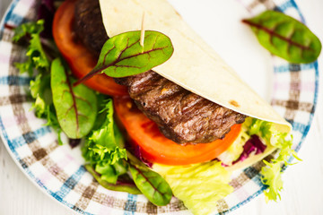 Mexican tortilla stuffed with beef steak and salad and vegetables