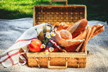 Picnic basket filled with fruit , bread and jar with apricot jam
