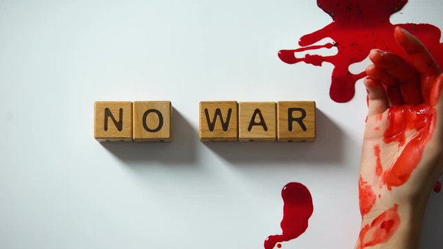 No war phrase made of wooden cubes, bleeding hand on table, political conflict