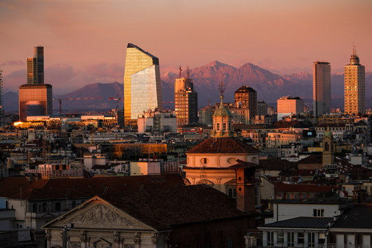 Milan skyline with skyscrapers at sunset. Aerial view of Milano city, Italy. The Grigne mountain range (Lombardy Alps) in the background. Italian landscape panorama.