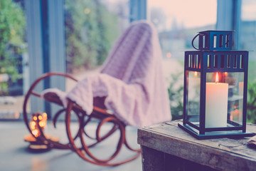 Lampion, bougie et chaise à bascule dans une ambiance cocoon à la maison.
