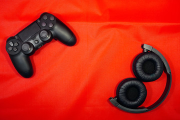 Collapsible headphones and gamepad on red isolated template texture background