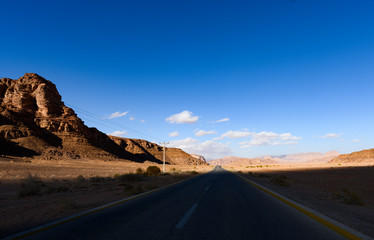 Kings highway, beautiful curvy road running through the Wadi Rum desert with rocky mountains in the distance in Jordan.