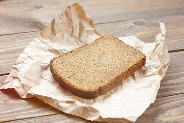 Dark bread with crumbs on wood board.Kraft paper.Crust bread