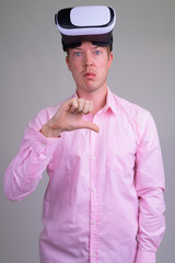 Upset young businessman with virtual reality headset and giving thumbs down