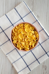 Cornflakes in a pink bowl for breakfast over white wooden background, top view. Flat lay, overhead, from above.