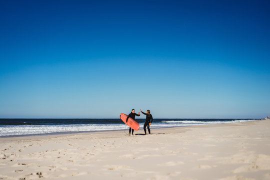 surf instructor with a student on the ocean. Surfer in a wet suit with a training board. Nazare, Portugal.