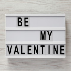 Modern board with text 'Be my Valentine' on a white wooden surface. Valentine's Day 14 February.
