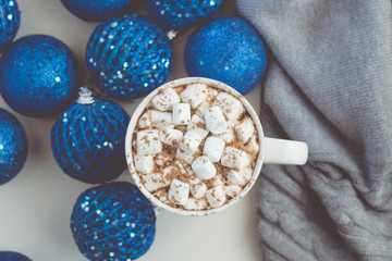 Cocoa mug with marshmallows on the background of blue christmas balls