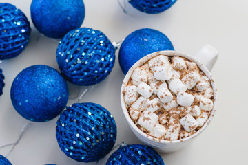 Cocoa mug with marshmallows on the background of blue christmas balls