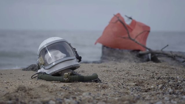 dead astronaut on the planet. The skull from the head in the helmet lies on the sand by the sea. Troubled by accident.