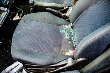 The seat of a vandalized car with broken smashed glass covering the seat