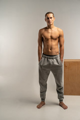 A shortcut hair man with a naked body in gray pants