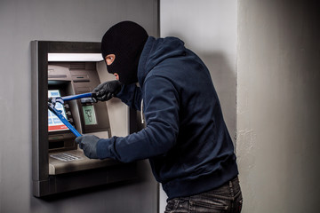 Thief with bolt cutter hacks an ATM. Law and crime concept