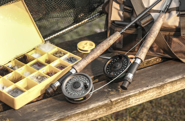 Fishing reels, rods and flies on wooden bench