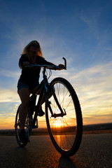 Fototapeta premium Woman riding a mountain bike at sunset. Sport and active life concept. 