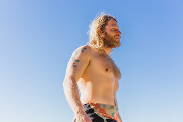 man with long white hair, in a baseball cap, looking into the distance, a portrait. surfer.