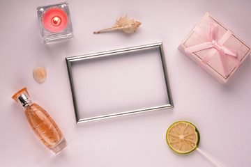 Purple background with frame for photo, gift box, candle and perfume, with empty space