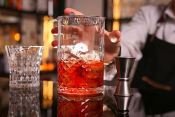 Professional bartender prepairing orange cocktail 