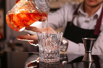 Professional bartender prepairing orange cocktail 