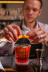 Professional bartender prepairing orange cocktail 