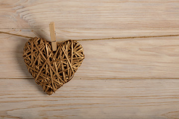 Happy Valentine's Day! Decorative wicker hearts of gold color on a light wooden background.