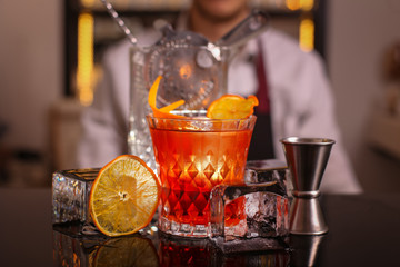 Professional bartender prepairing orange cocktail 
