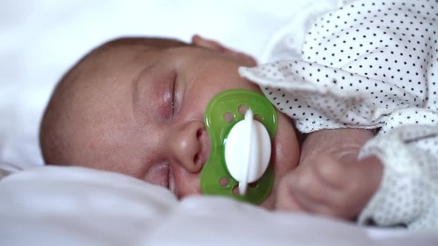 Newborn baby sleeps with pacifier in mouth