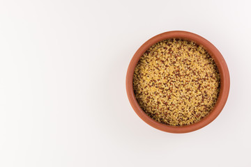 bowl of raw bulgur and quinoa isolated on white background, top view
