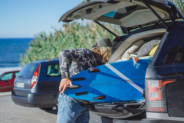 surfer man with long white hair in a cap and sunglasses with a surfboard. returns after surfing,...