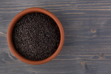 bowl of black wild rice on wooden table background, top view