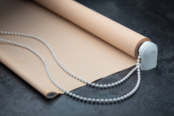 The roller blind lies on a black stone surface.