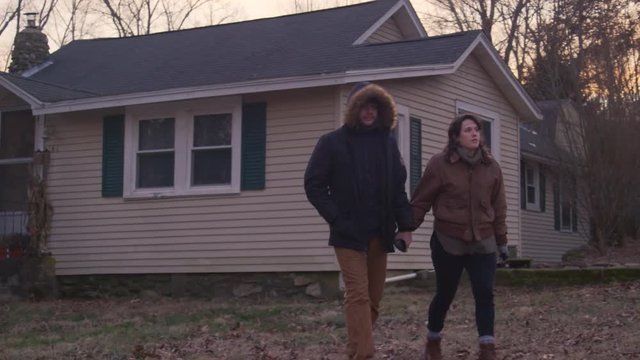 Young Romantic Couple Of Homeowners Walk Away From Home At Sunset