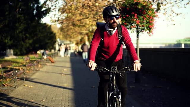 Businessman commuter with electric bicycle traveling from work in city. Slow motion.