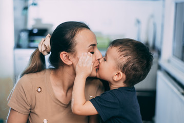 mom and son prepare flour dough and kiss