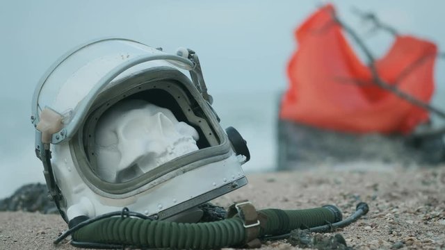 dead astronaut on the planet. The skull from the head in the helmet lies on the sand by the sea. Troubled by accident.